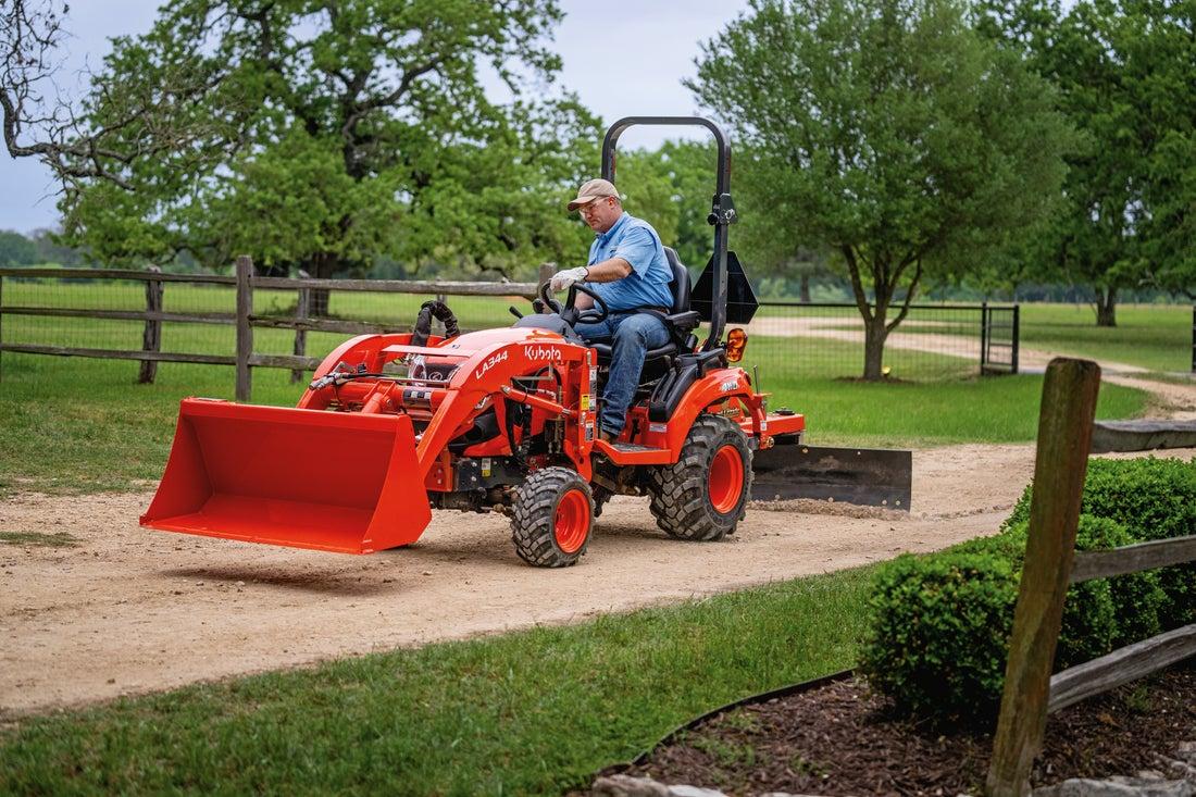 Man is using a blade implement on tractor for his dirt driveway