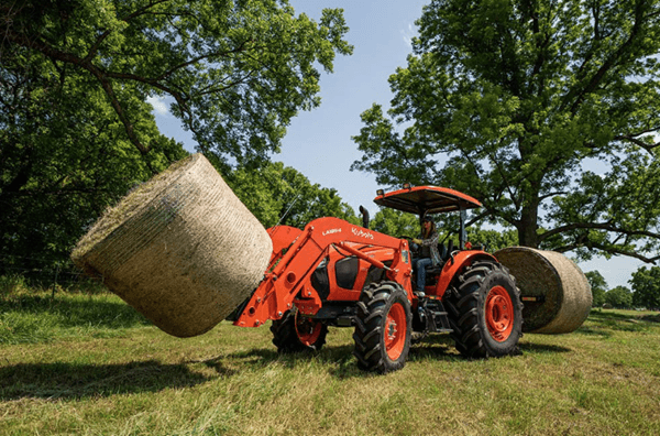 Tractor moving two large hay bales