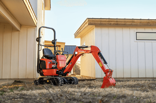 Staged image of compact excavator outside of building
