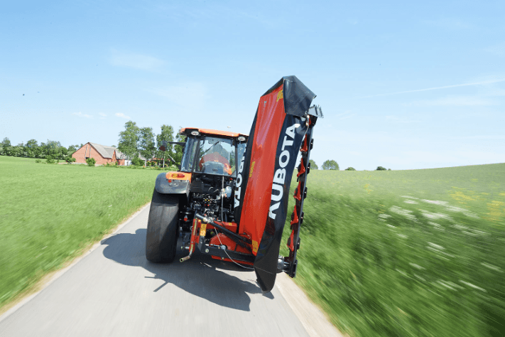 Disc mower attached to tractor that's driving down the road