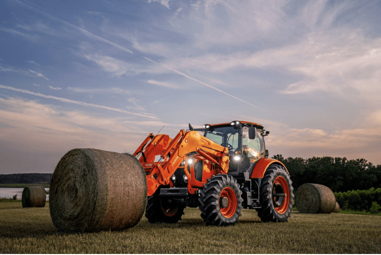Tractor picking up large hay bale