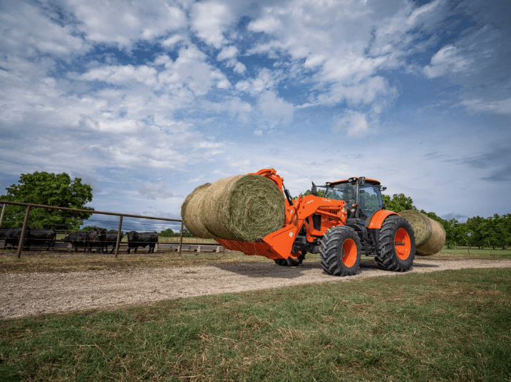 Tractor moving large hay bale