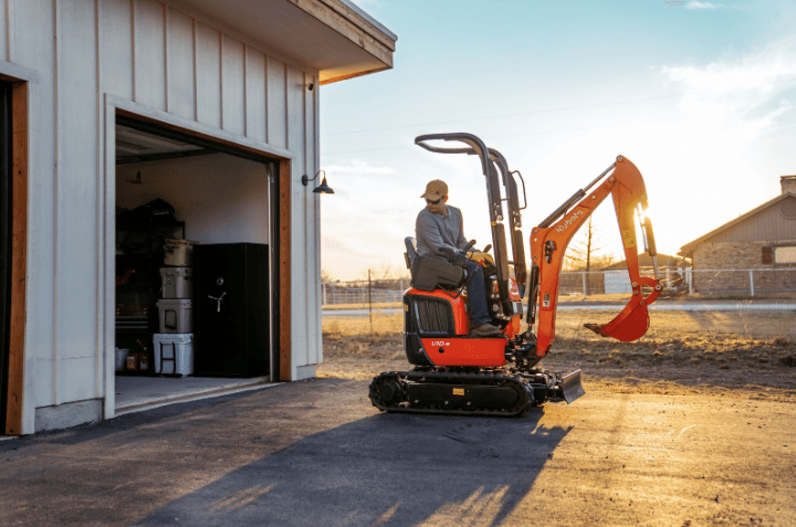 Man driving an excavator out of storage