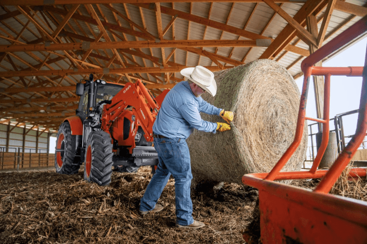 Farmer cutting open a large hay bale