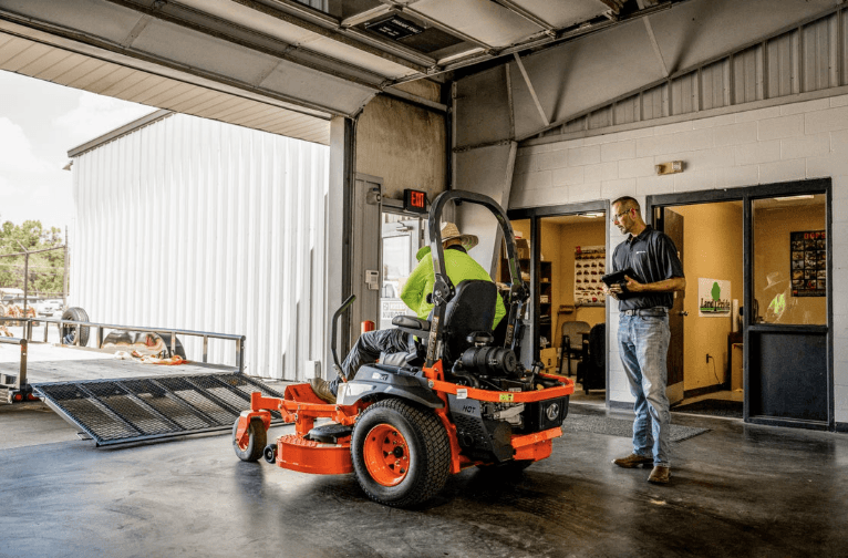 Landscaping team loading up mower onto trailer