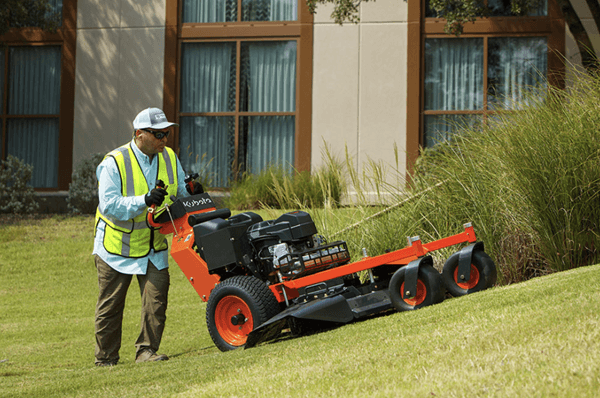Professional pushing walk-behind mower mowing up a hill