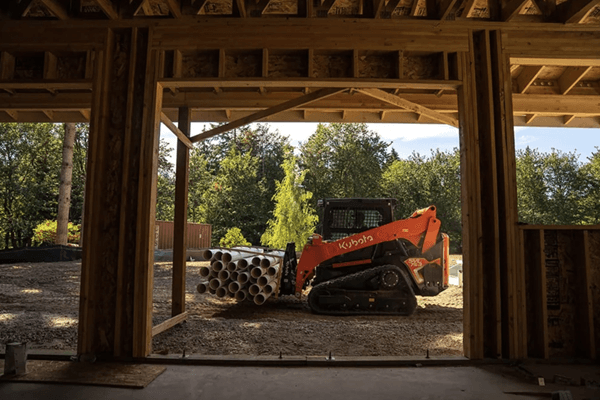 Track Loader moving pipes with front attachment